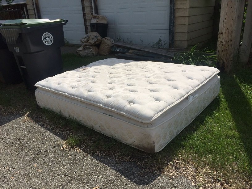 Old mattress left on the curb awaiting pickup, ideal example for Mattress Removal Services Kent WA.